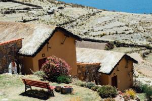 a bench in front of a building with a grass roof at Ecolodge La Estancia in Comunidad Yumani