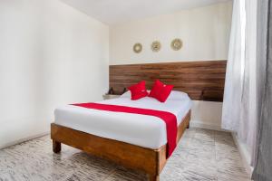 a bedroom with a large bed with red pillows at Hotel Suites Puebla in Puebla