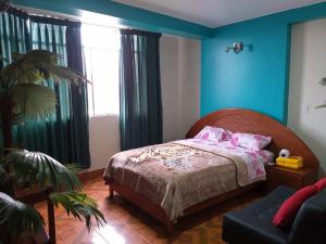 um quarto com paredes azuis e uma cama com almofadas cor-de-rosa em Hotel Camino Real em Chimbote