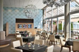 a restaurant with tables and chairs and a chandelier at Coast Chilliwack Hotel by APA in Chilliwack