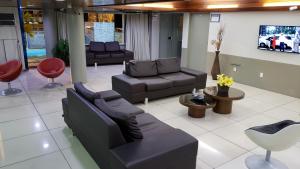 JR Hotel في جواو بيسوا: غرفة معيشة مع كنب وكراسي وتلفزيون