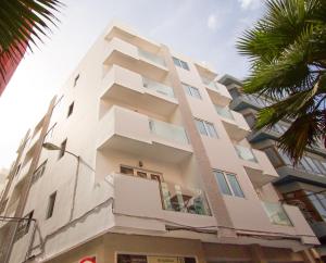 a tall white building with a palm tree at Boutique Home Canteras in Las Palmas de Gran Canaria