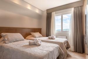 zwei Betten in einem Zimmer mit Fenster in der Unterkunft Via Florida Luxo II - 303 in Gramado