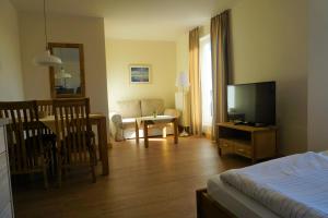 a living room with a bed and a living room with a television at Parkhotel Seeblick in Warnemünde