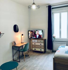 a bedroom with a tv and a table and a bed at Studio Cosy Family in Roanne