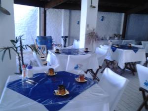 uma sala com mesas brancas e cadeiras brancas com comida em Vargas Peruibe Hotel em Peruíbe