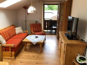 ein Wohnzimmer mit einem Sofa, einem Tisch und einem TV in der Unterkunft FeWo Sonnwend in Schönau am Königssee