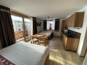 a room with a bed and a kitchen with a table at Mont Chalet Apartaments in Livigno