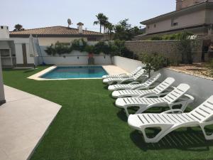 a row of white lounge chairs next to a swimming pool at Apartamento Centrico en Albir in Albir