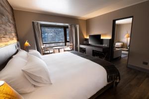 a bedroom with a large white bed with a desk and a window at Hotel Termas Chillán in Nevados de Chillan