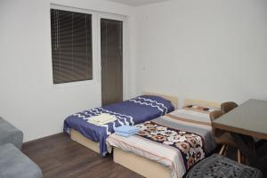 two beds in a room with a table and a window at Markos Towers Apartments in Prilep