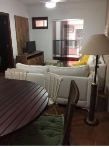 ein Wohnzimmer mit einem Sofa und einem Tisch in der Unterkunft Apartamento em Ubatuba, confortavel e bem localizado in Ubatuba