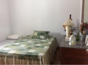 ein Schlafzimmer mit einem Bett und einem Tisch mit einer Lampe in der Unterkunft Apartamento em Ubatuba, confortavel e bem localizado in Ubatuba