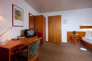 a hotel room with a desk with a television and a bed at Pension Cafe Suzette in Gotha
