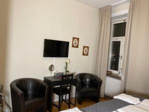 um quarto de hotel com uma secretária e cadeiras e uma televisão em Hotell Göta em Örebro