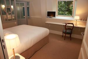 a bedroom with a bed and a desk and a chair at Hôtel Le Gentleman in La Flèche