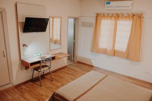 um quarto com uma cama, uma secretária e uma televisão em Motel ACA Santa Rosa em Santa Rosa