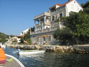a large white house with two boats in the water at Apartments Mile - 10m from the sea in Lastovo