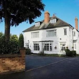 a white house with a tree in front of it at Charnwood Regency Guest House in Loughborough