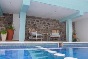 a swimming pool with two chairs and a table at Villas Pura Chacala in Chacala