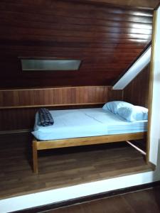 a bed in a room with a wooden wall at HOSTEL DU SUCA in Petrópolis