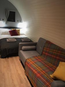 a bed and a couch in a room with a bed and a couch at Tomatin Glamping Pods in Inverness