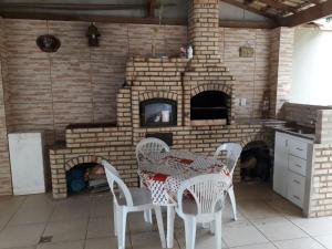 ein Esszimmer mit einem Tisch und einem gemauerten Kamin in der Unterkunft Casa de Temporada no Centro de Cabo Frio in Cabo Frio