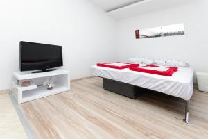 a white bedroom with a bed and a flat screen tv at City Apartments Nada in Makarska