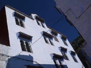 a tall white building with windows on it at Hôtel Ras El Maa in Chefchaouene