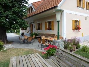 un patio con mesa y sillas frente a una casa en Farm Stay Rotovnik - Plesnik en Slovenj Gradec