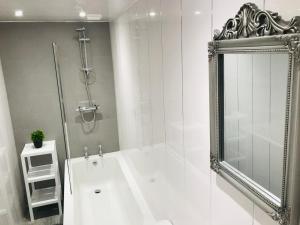 a white bathroom with a shower and a white tub at THE LION’S REST - BOUTIQUE APARTMENT SUITE. in Port Glasgow