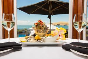 una mesa con un plato de comida y dos copas de vino en The Sands Hotel Hokianga, en Opononi