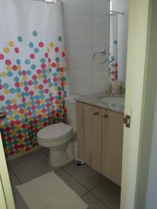 a bathroom with a toilet and a colorful shower curtain at Departamento Familiar Los Molles in Los Molles