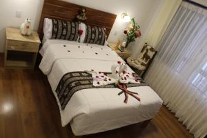 Un dormitorio con una gran cama blanca con flores. en Cusco Hostal Qolla Wasi, en Cusco