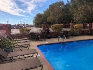 a swimming pool with chairs and a table and a fence at Best Western Rayne Inn in Rayne