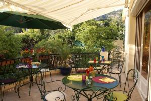 un patio con mesas, sillas y una sombrilla en Hôtel Restaurant Les oliviers, en Nyons