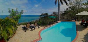 a swimming pool with chairs and a view of the ocean at Montezuma Heights in Montezuma