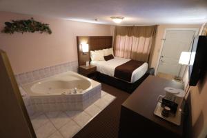 um quarto de hotel com uma cama e uma banheira em Campbellford River Inn em Campbellford