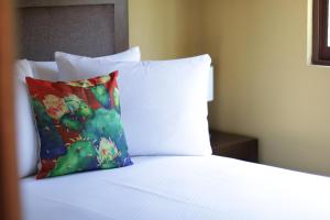 a bed with white sheets and a colorful pillow at Casa Flores Hotel & Spa in Atlixco