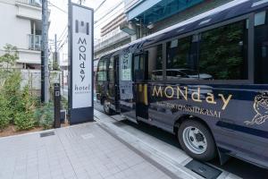 um autocarro está estacionado ao lado de uma paragem de autocarro em hotel MONday Tokyo Nishikasai em Tóquio