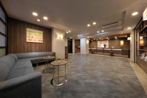 a lobby with a couch and tables in a building at Keio Presso Inn Ikebukuro in Tokyo