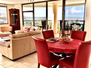 Cairns Apartment Esplanade Ocean Views في كيرنز: غرفة معيشة مع طاولة حمراء وكراسي