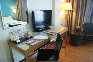 a hotel room with a desk with a television on it at Tang Dynasty Bay Hotel in Kota Kinabalu