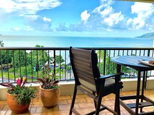 Cairns Apartment Esplanade Ocean Views في كيرنز: شرفة مع مقعد وطاولة والمحيط