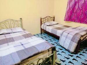 two beds sitting next to each other in a room at Homestay Bandar Pekan - musleem preferred in Pekan