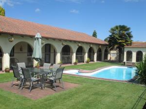 a patio with a table and chairs next to a pool at Captains Quarters Motor Inn in Cambridge