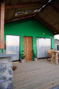 a green house with a table and a wooden floor at The green and red cabins in Ma'ale Gamla