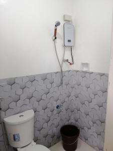 a bathroom with a toilet and a hair dryer on the wall at Katrina's Dorm in Tarlac