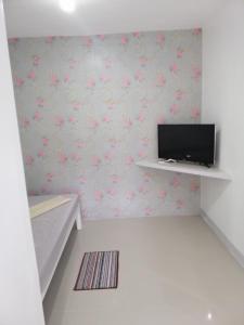 a room with a tv on a wall with flowers at Katrina's Dorm in Tarlac