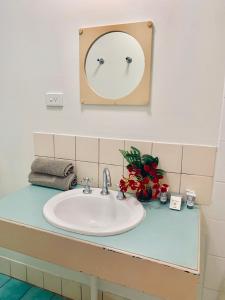 
a bathroom with a sink, mirror, and flowers on the wall at Roebuck Bay Hotel in Broome
